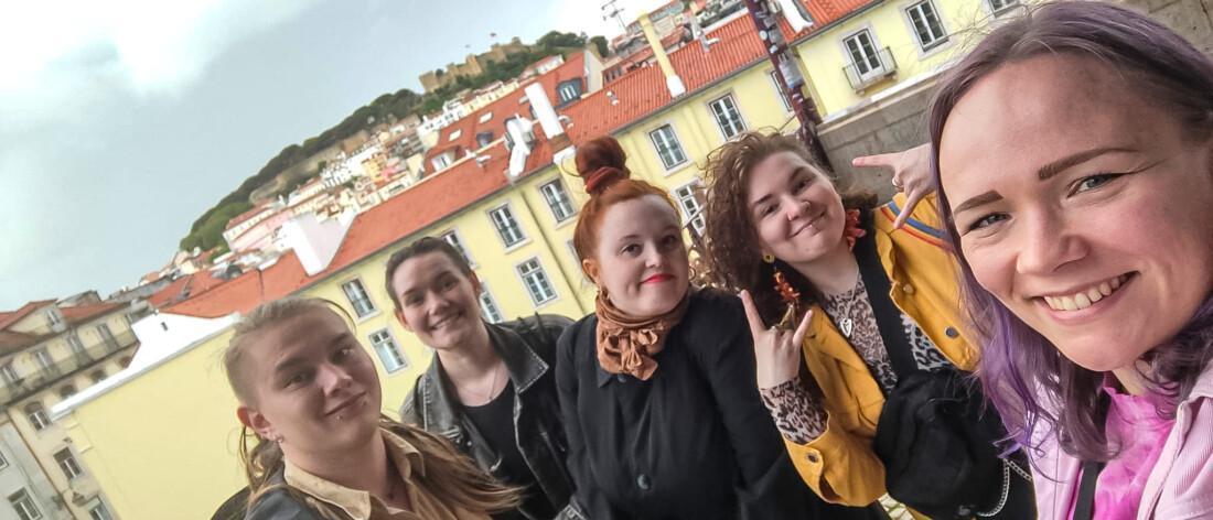 Viisi hankkeen osallistujaa yhteiskuvassa Lissabonissa. Taustalla näkyy vaaleita rakennuksia punaisine kattotiilineen sekä kaupungin mäkinen maisema.