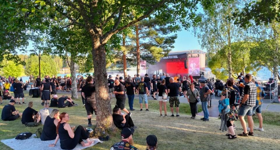 Ihmisjoukko ulkoilmassa John Smith -festareilla nurmikolla puiden alla.