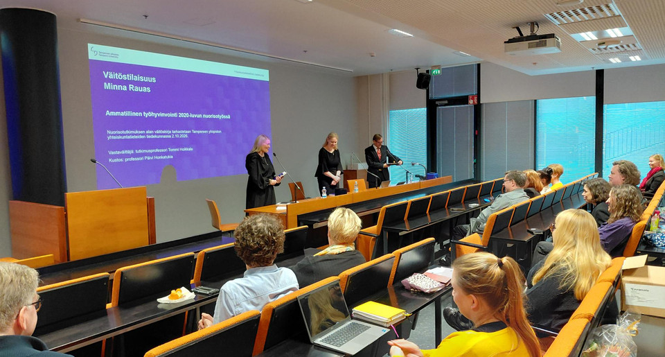 Yleisöä istumassa luentosalissa kuuntelemassa väitöstilaisuutta.
